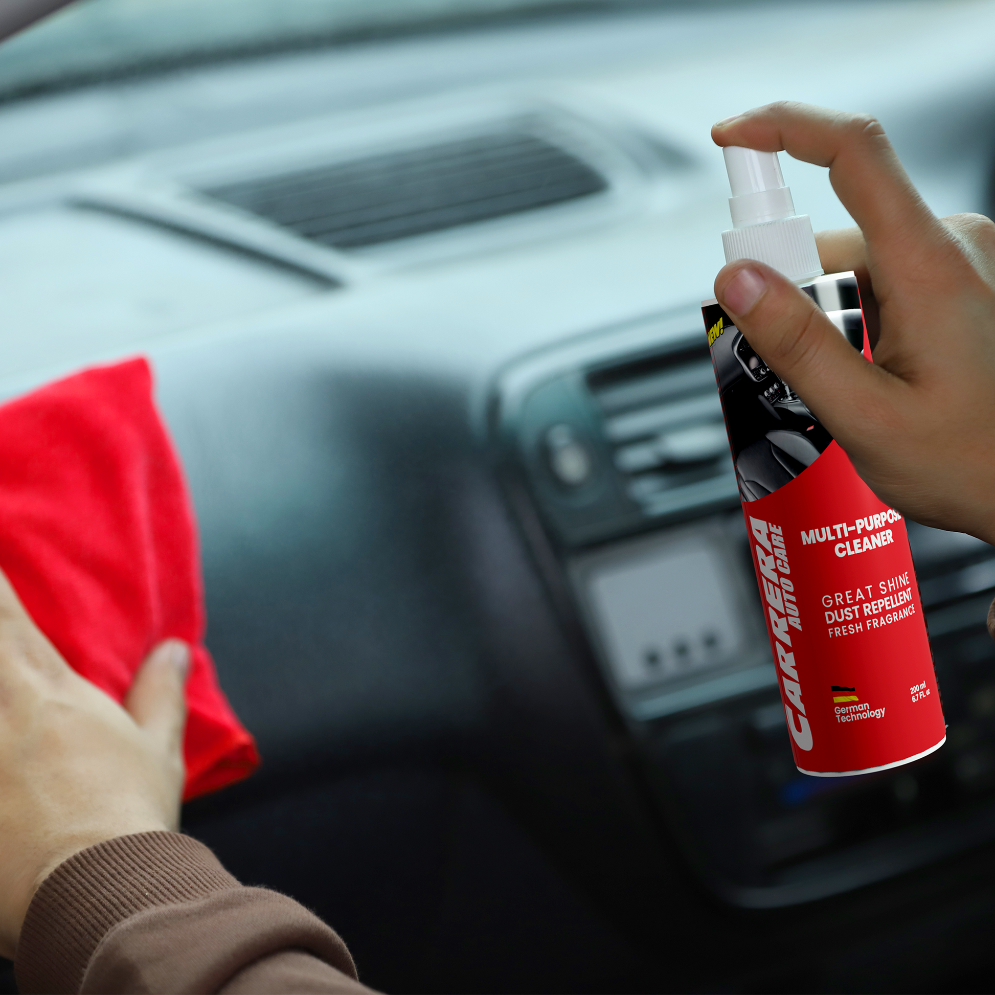 a person spraying carrera dashboard cleaner on his car dashboard